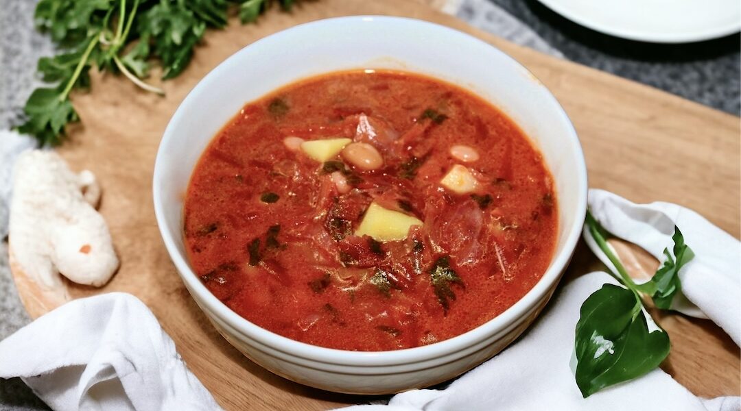 Barszcz ukraiński to zupa przygotowana na wywarze jarzynowym z dodatkiem startych buraków, marchewki, kapusty, ziemniaków i białej fasolki doprawiona na koniec kwaśną śmietaną.