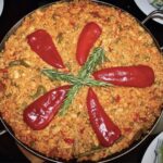 Paella Valenciana to tradycyjna potrawa hiszpańska z mięsa i warzyw z dodatkiem ryżu z szafranem i mieloną papryką.