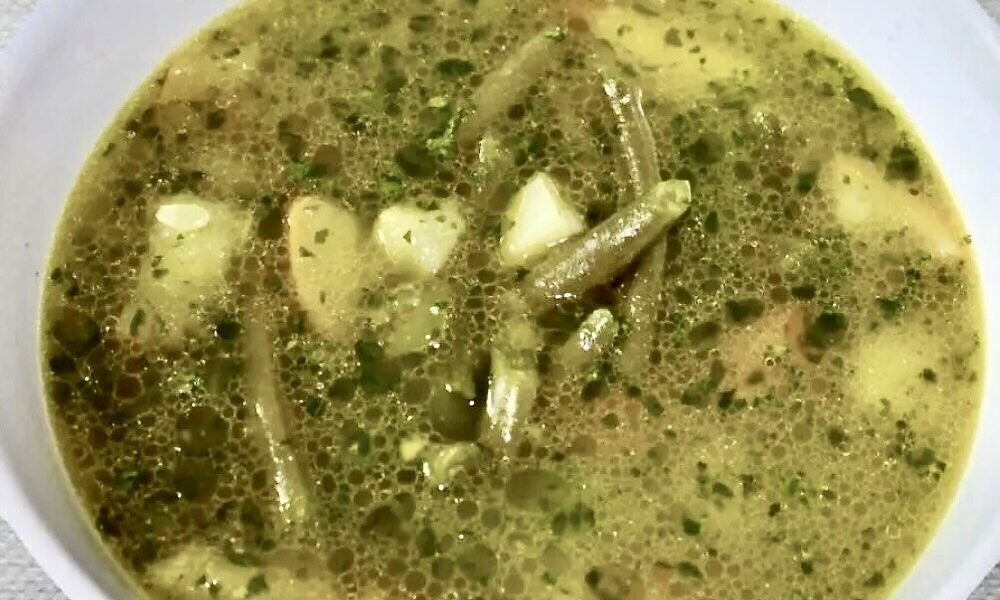 Zupa jarzynowa na bazie bulionu warzywnego z dodatkiem fasolki szparagowej, bobu i cukinii doprawiona domowym pesto bazyliowym.