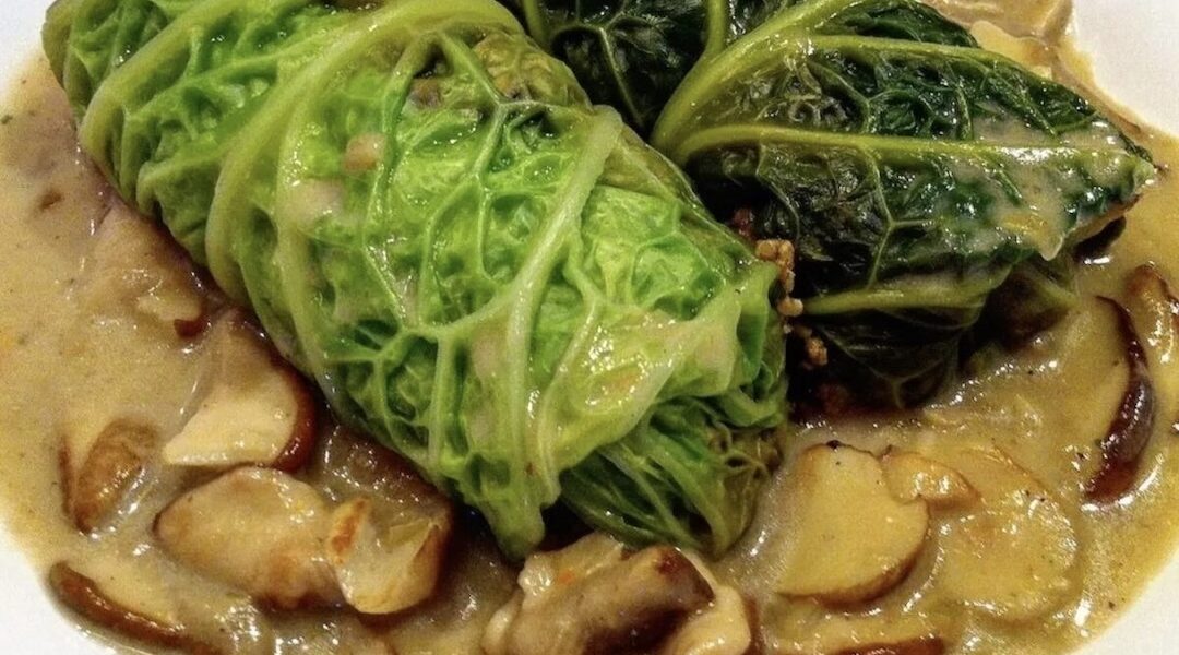 Gołąbki wegetariańskie to liście kapusty włoskiej wypełnione farszem ze świeżych i mielonych grzybów z dodatkiem kaszy jaglanej, zawinięte, duszone i podane w sosie grzybowym.