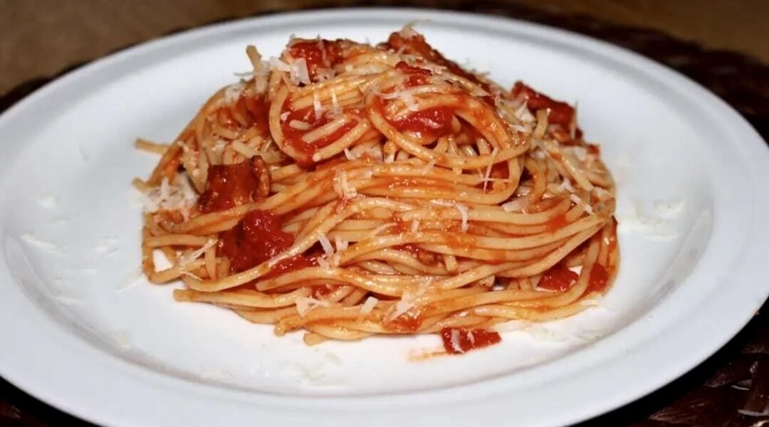 Spaghetti amatriciana, czyli spaghetti pochodzące z włoskiego miasta Amatrice, z aksamitnym sosem pomidorowym przygotowanym na aromatycznym podgardlu wieprzowym i posypane startym serem owczym pecorino.