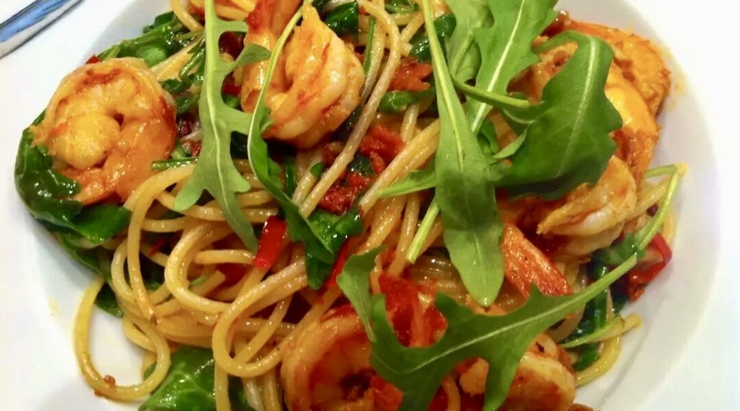 Makaron spaghetti ze smażonymi z czosnkiem i chilli krewetkami, pomidorami i świeżą rukolą.
