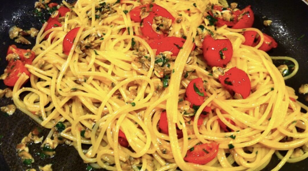 Makaron spaghetti podany ze świeżymi małżami z czosnkiem i pomidorkami koktajlowymi.