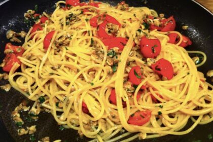 Makaron spaghetti podany ze świeżymi małżami z czosnkiem i pomidorkami koktajlowymi.