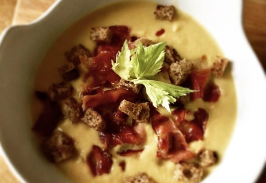 Aromatyczna zupa krem z kalafiora przyrządzona na wywarze jarzynowym z dodatkiem sera, podana z grzankami i chrupiącą szynką.