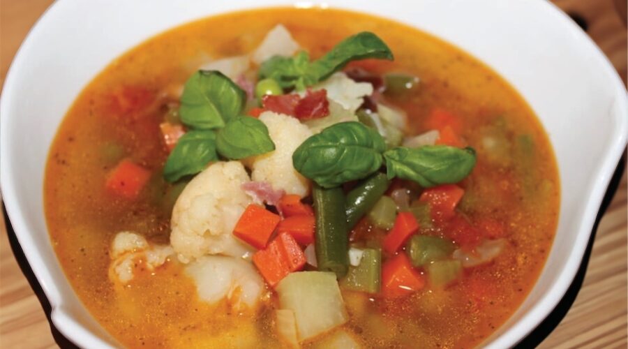 Zupa minestrone, czyli włoska zupa jarzynowa w wersji zimowej przygotowana na domowym bulionie drobiowym zrobiona na soffritto i z dodatkiem mrożonych warzyw.