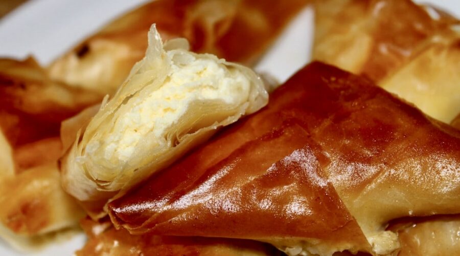 Greckie pierogi pierogi z serem przygotowane z ciasta filo wypełnionego serem lub mieszanką serów, pokrojonego na kawałki, złożonego w trójkąty i upieczonego.